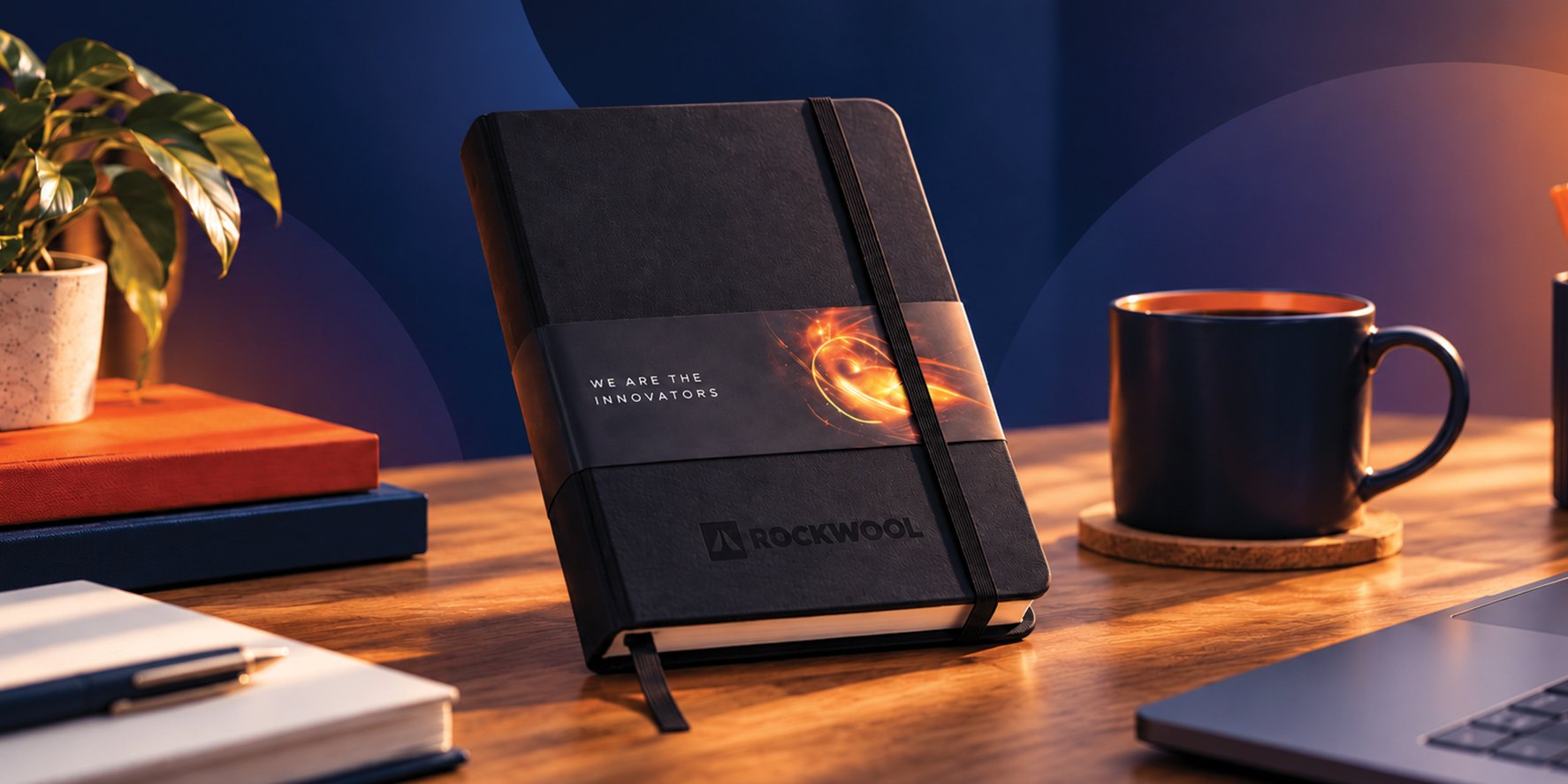 Branded ROCKWOOL notebook on a wooden desk next to a coffee cup