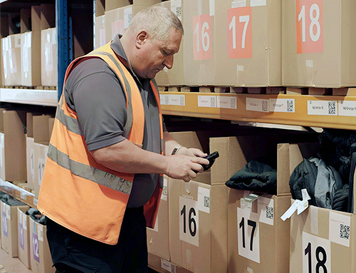 Warehouse team member scanning branded merchandise kits with a handheld scanner